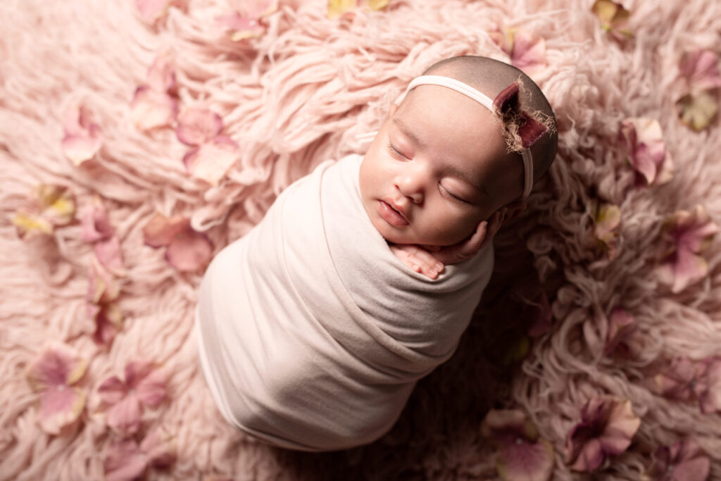 Newborn baby on flokati with rose petals