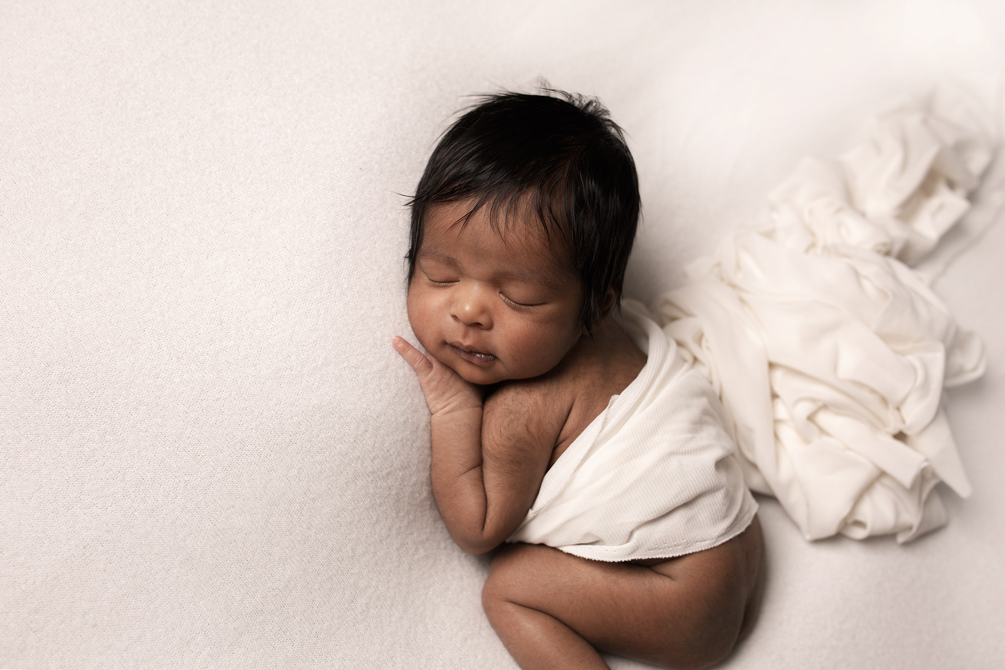 baby in white newborn posing